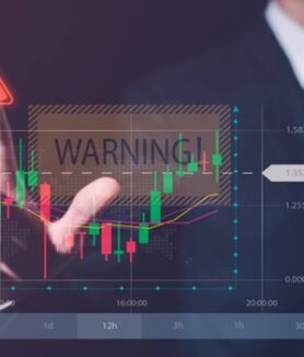 Person pointing at a financial chart with a 'Warning' sign, highlighting scam risks and issues with ECN.Broker.