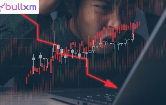 Businessman looking at a laptop screen with a red downward trend arrow, highlighting concerns about Bullxm's scam activities.